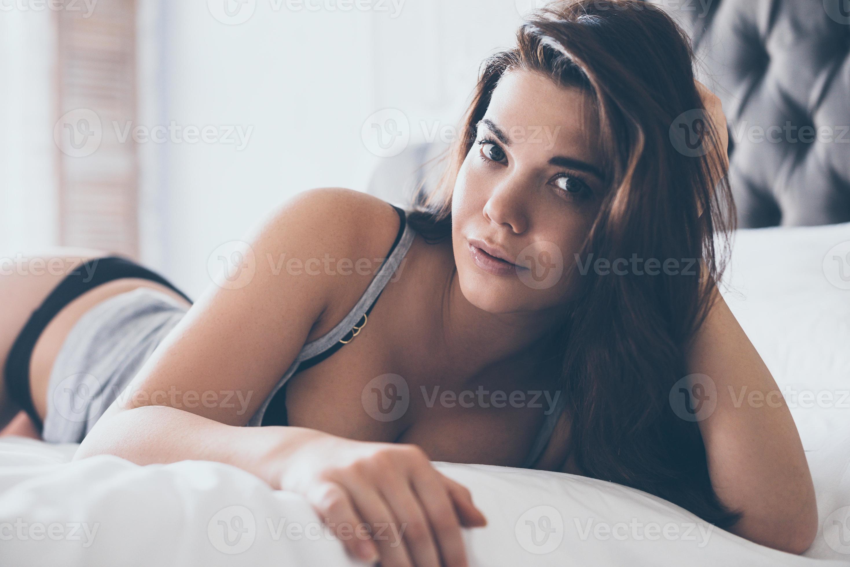 Carefree beauty. Beautiful young woman in black lingerie and tank top  looking at camera while lying on front in bed 13521597 Stock Photo at  Vecteezy