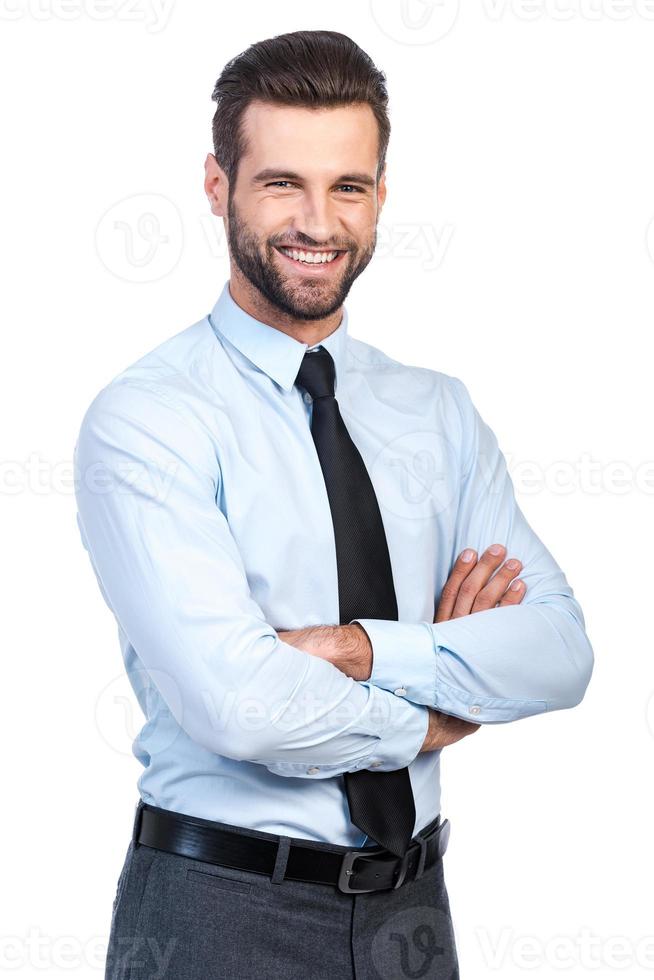 Confident business expert. Confident young handsome man in shirt and tie keeping arms crossed and smiling while standing against white background photo