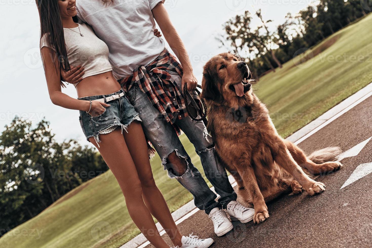 Couple with dog. Close-up of young modern couple with cute dog spending carefree time while standing outdoors photo