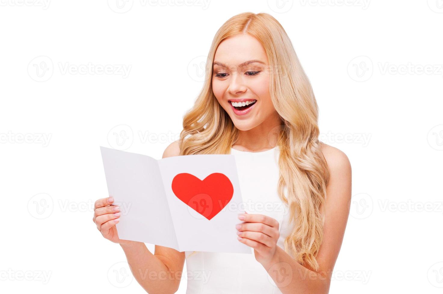 Valentine card from him. Beautiful young blond hair woman holding valentine card and smiling while standing isolated on white photo