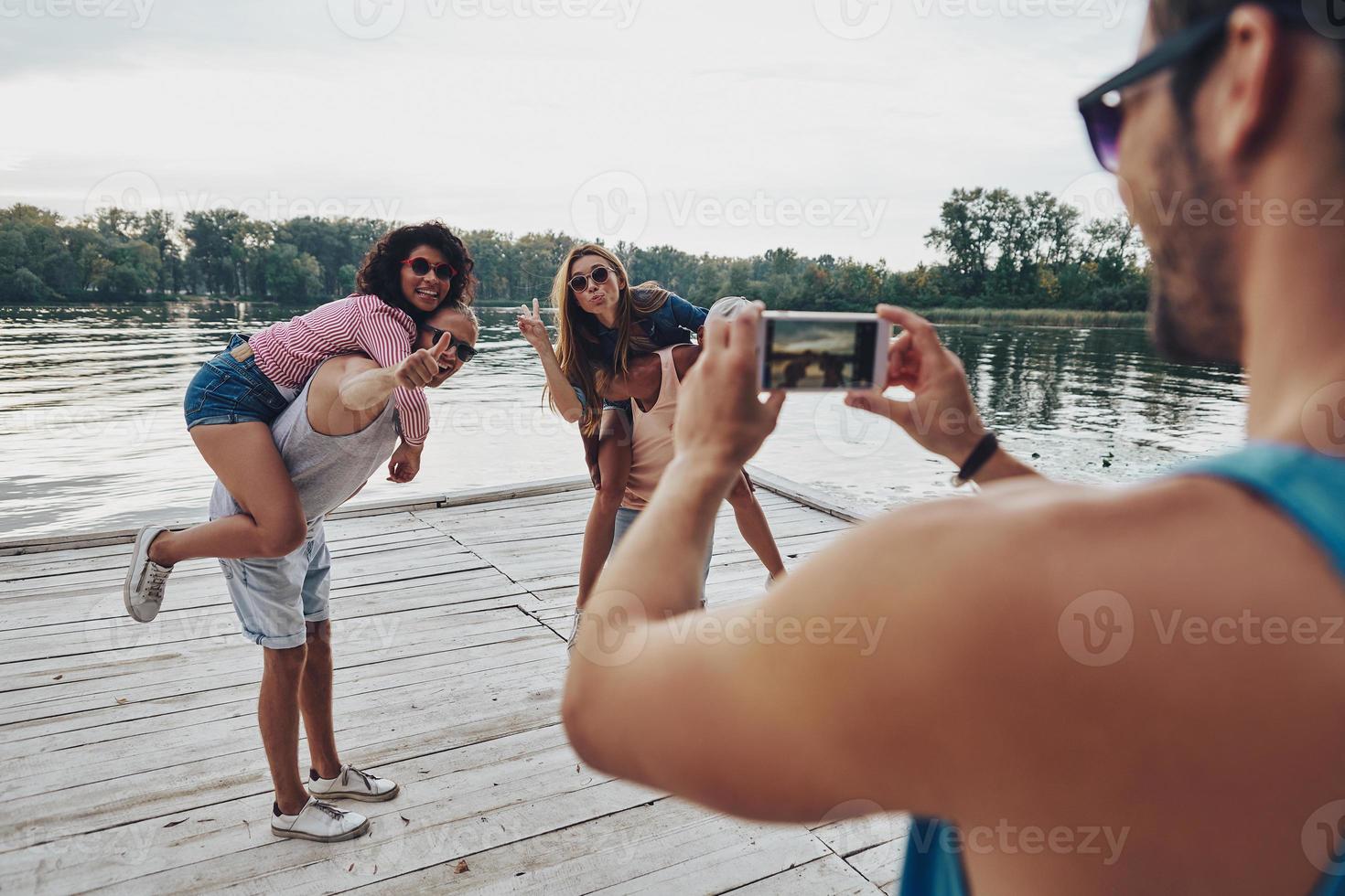 hermosas parejas jóvenes que pasan tiempo sin preocupaciones mientras están de pie en el muelle foto