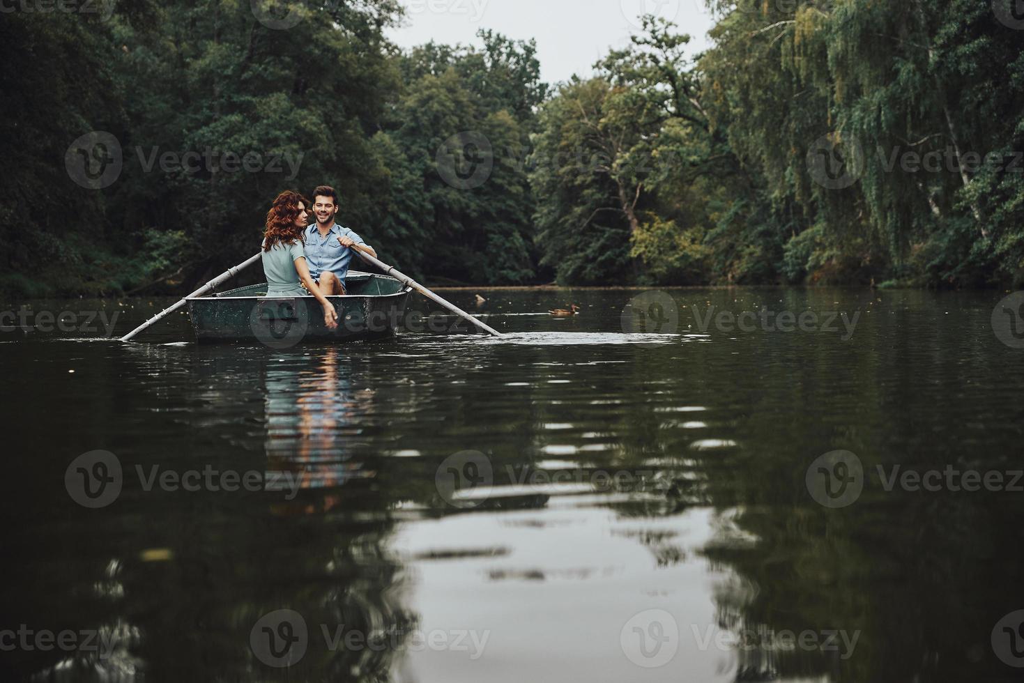 Enjoying every minute together. Beautiful young couple smiling while enjoying romantic date on the lake photo