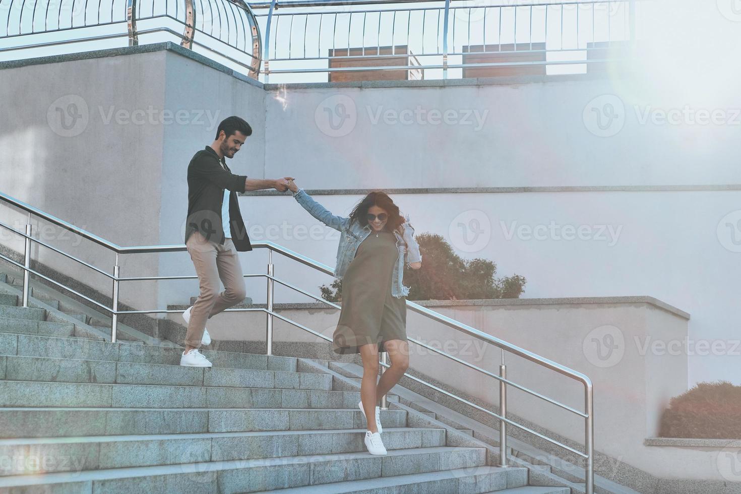 She is everything to him. Full length of handsome man and young attractive woman holding hands while walking down the stairs outdoors photo
