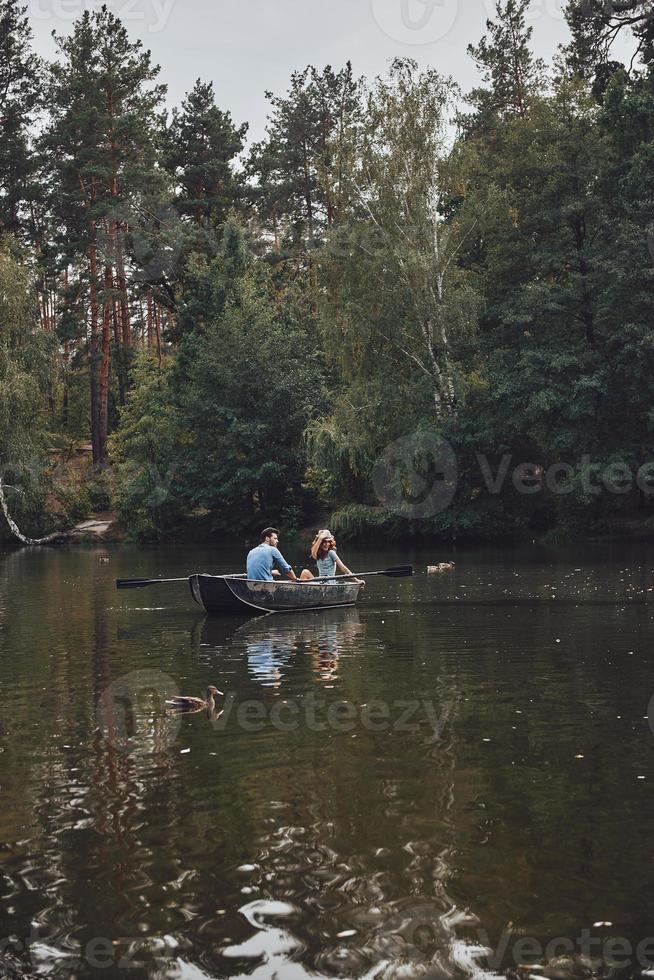 Little adventure. Beautiful young couple enjoying romantic date and smiling while rowing a boat photo