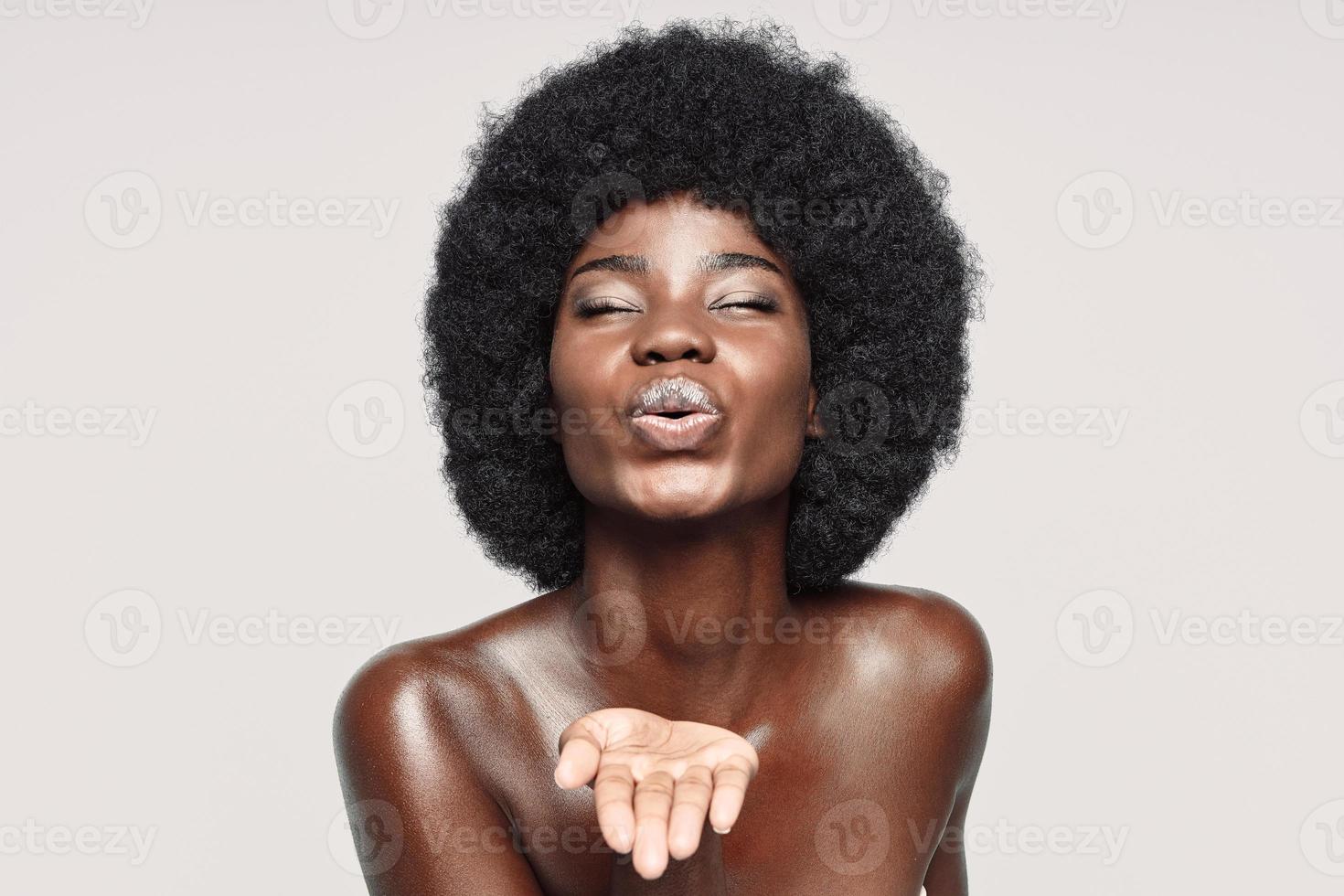 Portrait of beautiful young African woman keeping eyes closed and blowing a kiss photo