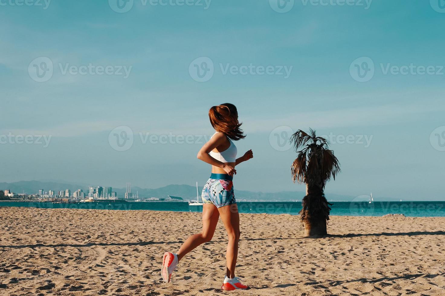 buen día para correr. toda la longitud de una hermosa joven con ropa deportiva trotando mientras hace ejercicio al aire libre foto