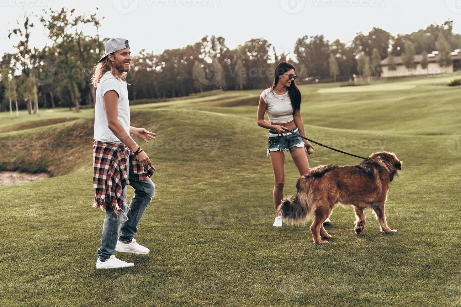 He is more than just a pet. Full length of beautiful young couple playing with their dog while spending time outdoors photo
