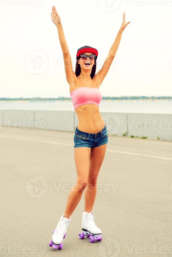Ready to fun. Full length of happy young woman wearing roller skates and keeping her arms outstretched photo