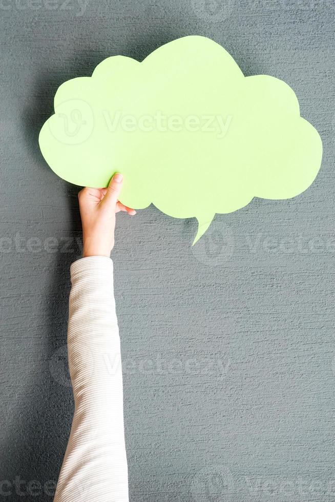 Copy space cloud. Close-up of woman stretching out empty speech bubble against grey background photo