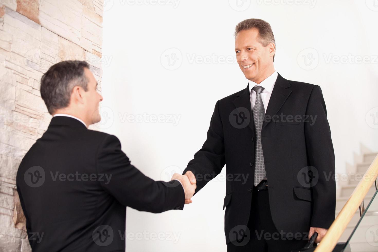 Handshake. Two business men in formalwear handshaking on staircase and smiling photo