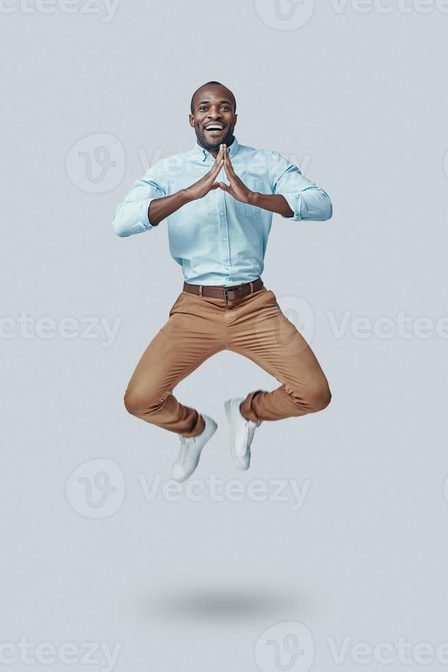 Playful young African man gesturing and shouting while hovering against grey background photo