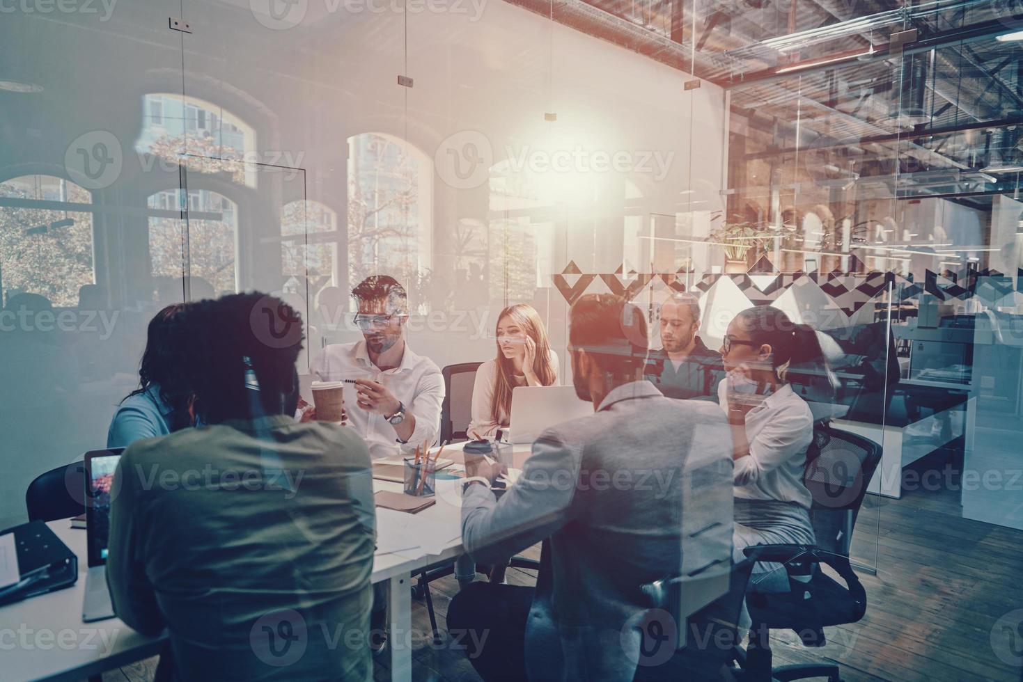 Group of young modern people in smart casual wear discussing business while working in the board room photo