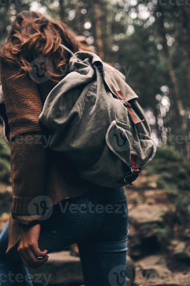 vista trasera de una mujer con mochila subiendo mientras camina por el bosque foto