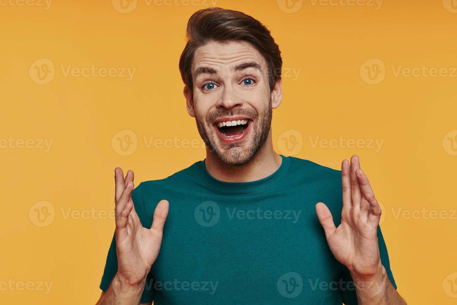 Handsome young smiling man in casual clothing looking at camera and gesturing photo