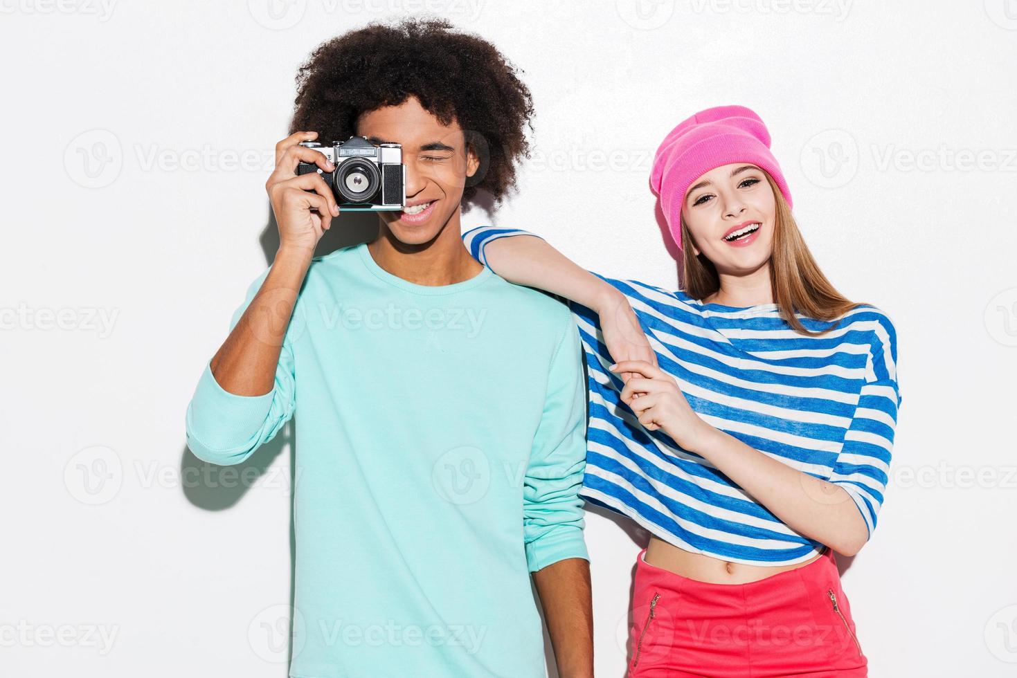 Spending great time together. Funky young couple smiling while standing against white background photo