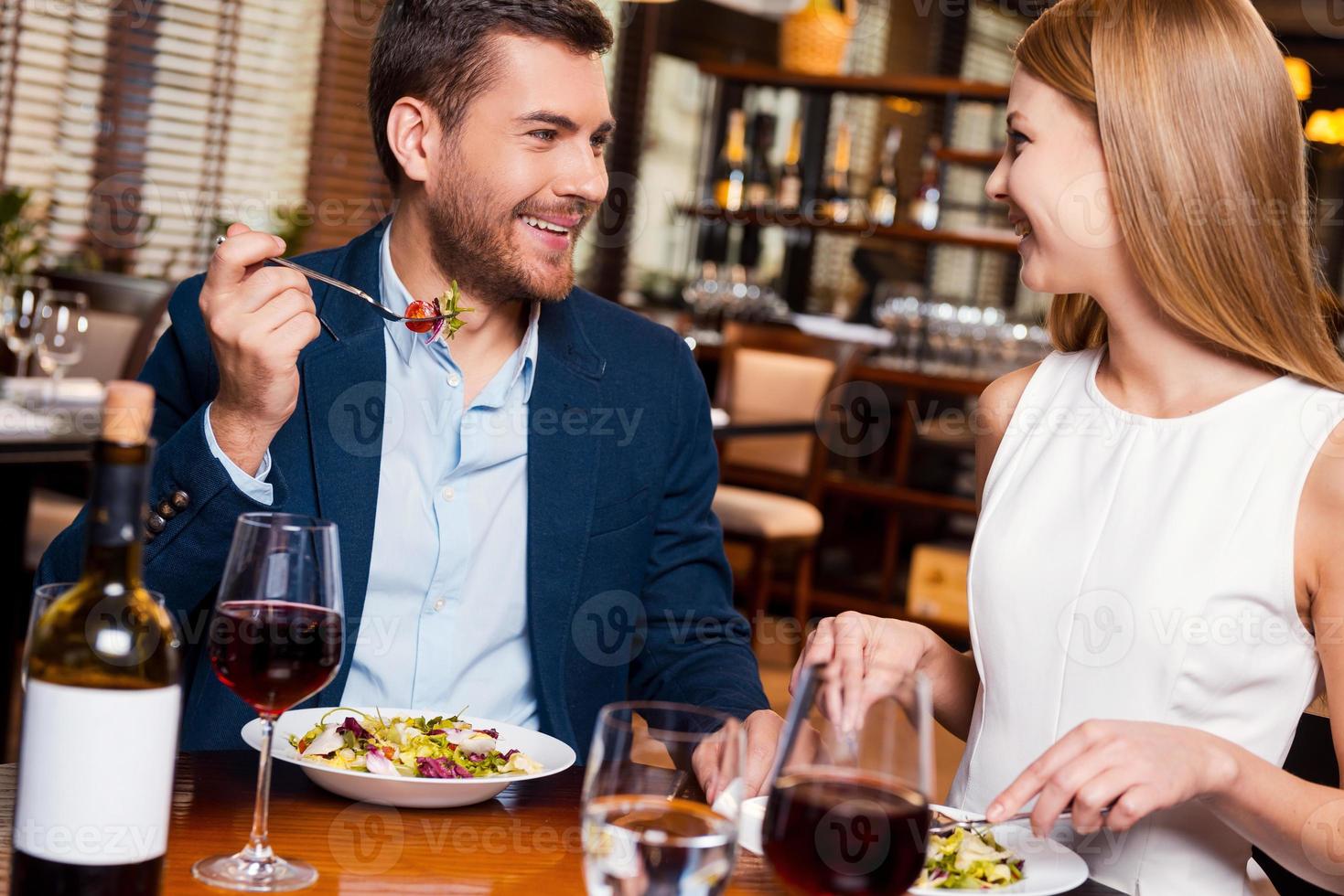 Enjoying meal together. Beautiful young loving couple enjoying dinner at the restaurant photo