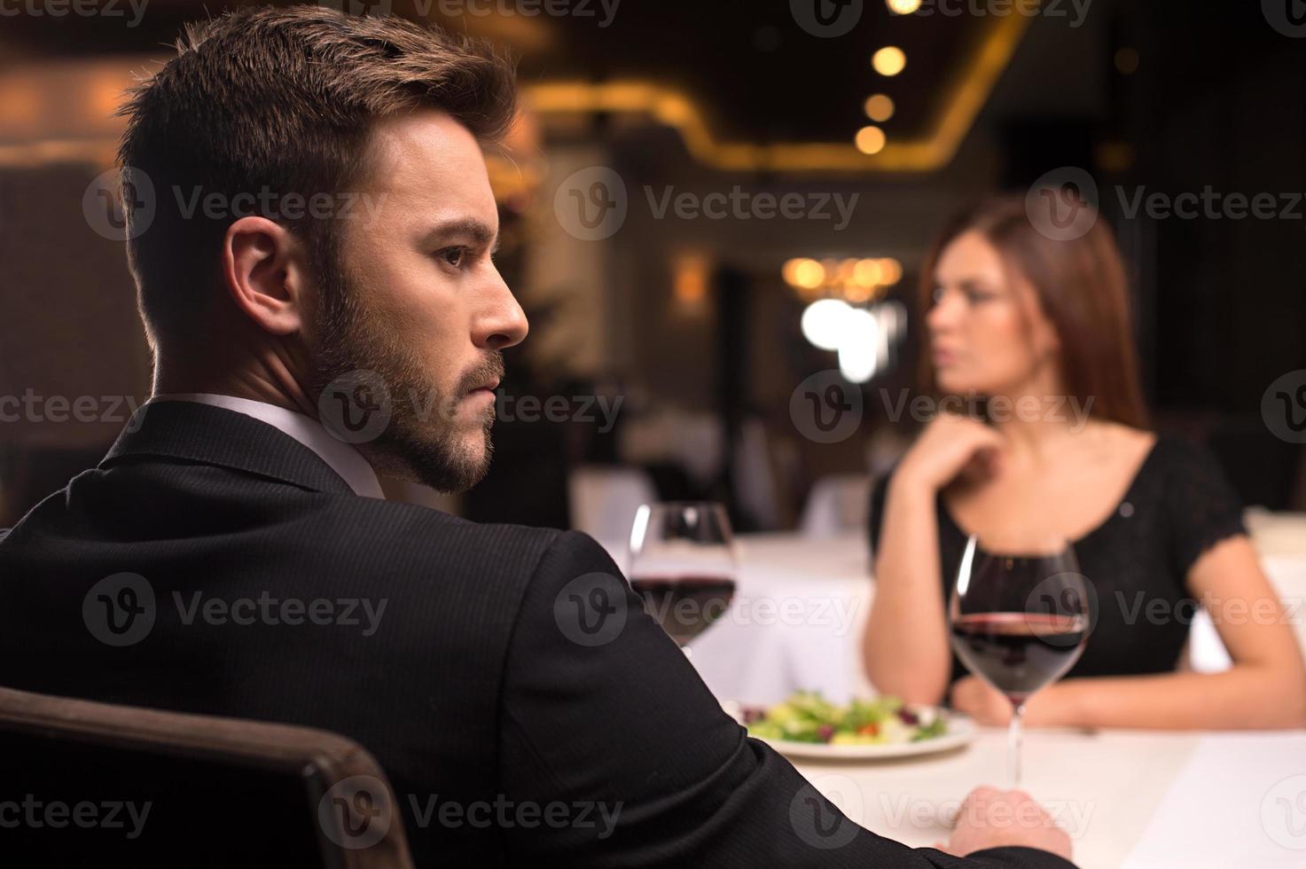 no mas palabras. pareja joven pensativa sentada en el restaurante y mirando hacia otro lado foto