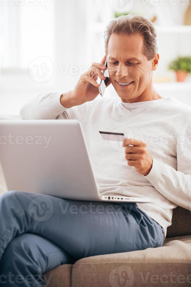 Shopping right from home. Cheerful mature man shopping online while sitting on the couch at home photo
