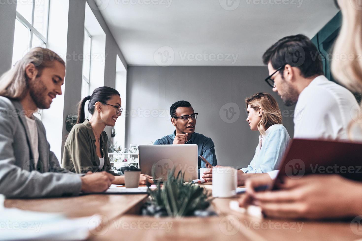 Passionate about their project. Group of young modern people in smart casual wear discussing business while working in the creative office photo