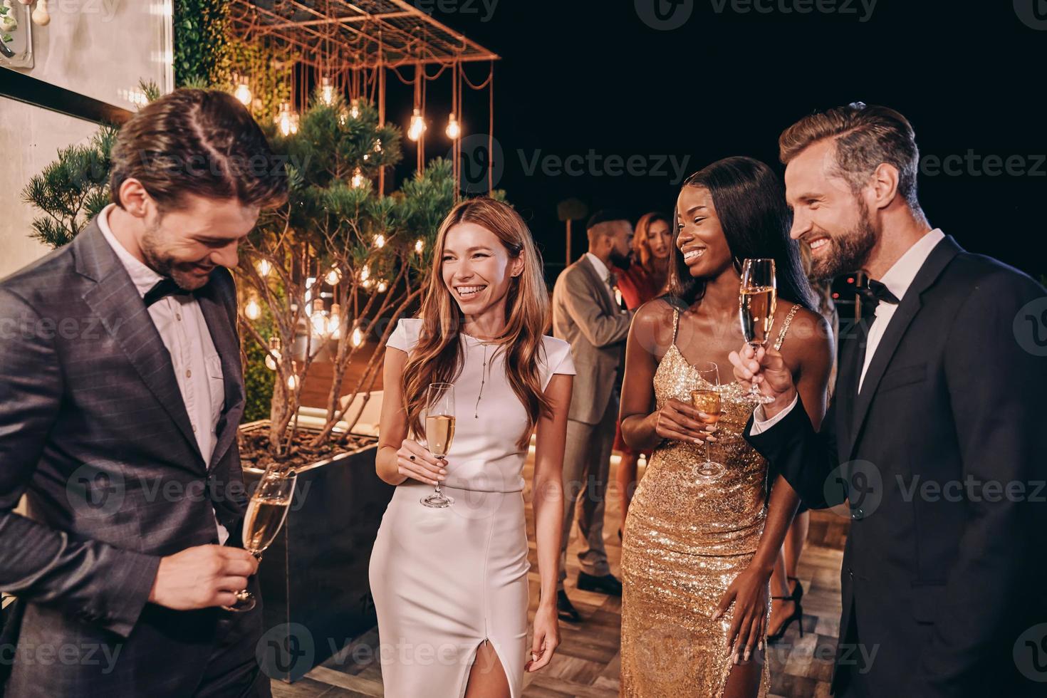 Group of beautiful people in formalwear communicating and smiling while spending time on luxury party photo