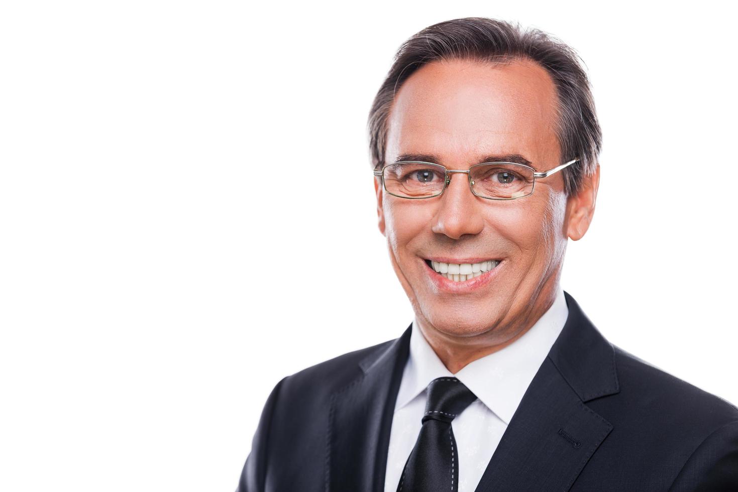 Confident and successful. Portrait of confident mature man in formalwear and eyeglasses looking at camera and smiling while standing against white background photo