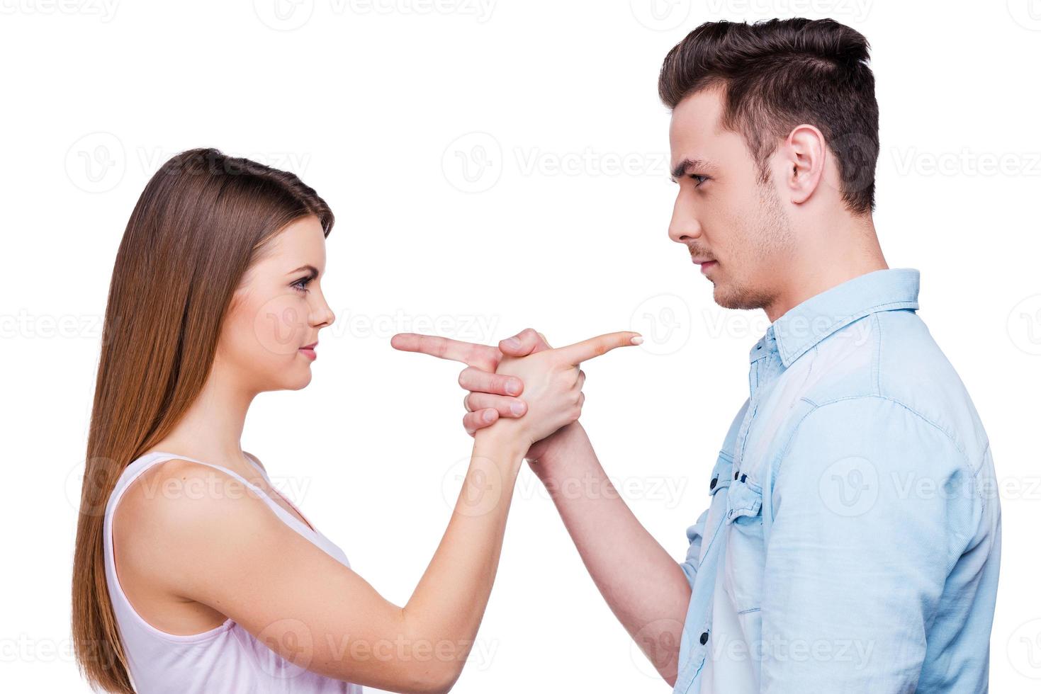 Mutual claims. Side view of beautiful young loving couple pointing each other while standing against white background photo