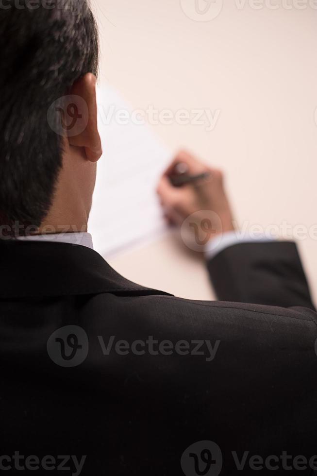 Contract signing. Rear top view of man in formalwear signing a document photo