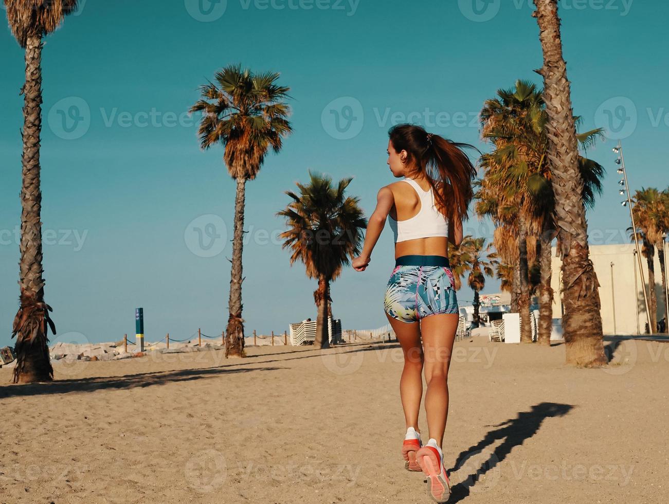 Power and balance. Rear view of beautiful young woman in sports clothing jogging while exercising outdoors photo