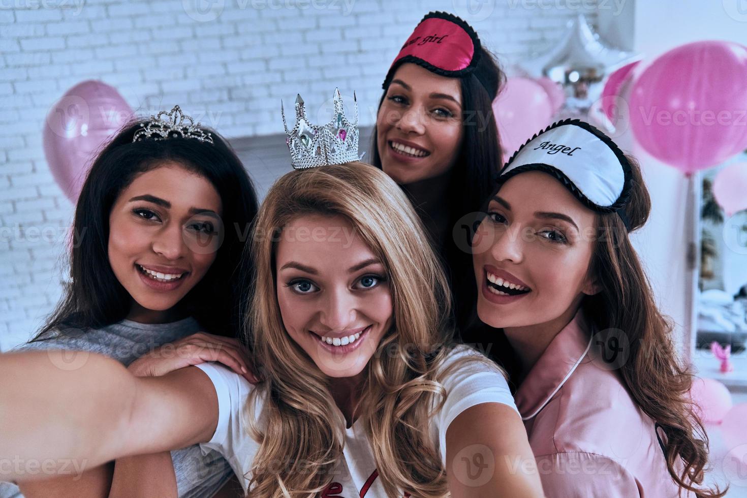 This one goes in frame. Self portrait of four playful young women smiling and looking at camera while having a slumber party photo