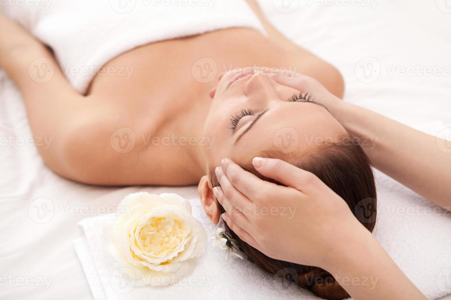 Total relaxation at spa. Attractive young woman lying on back while massage therapist massaging her head photo