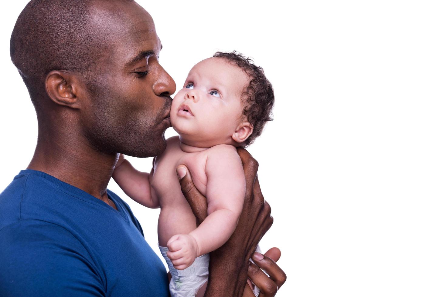 Father and baby. Young African man holding his little baby and kissing him while standing isolated on white photo