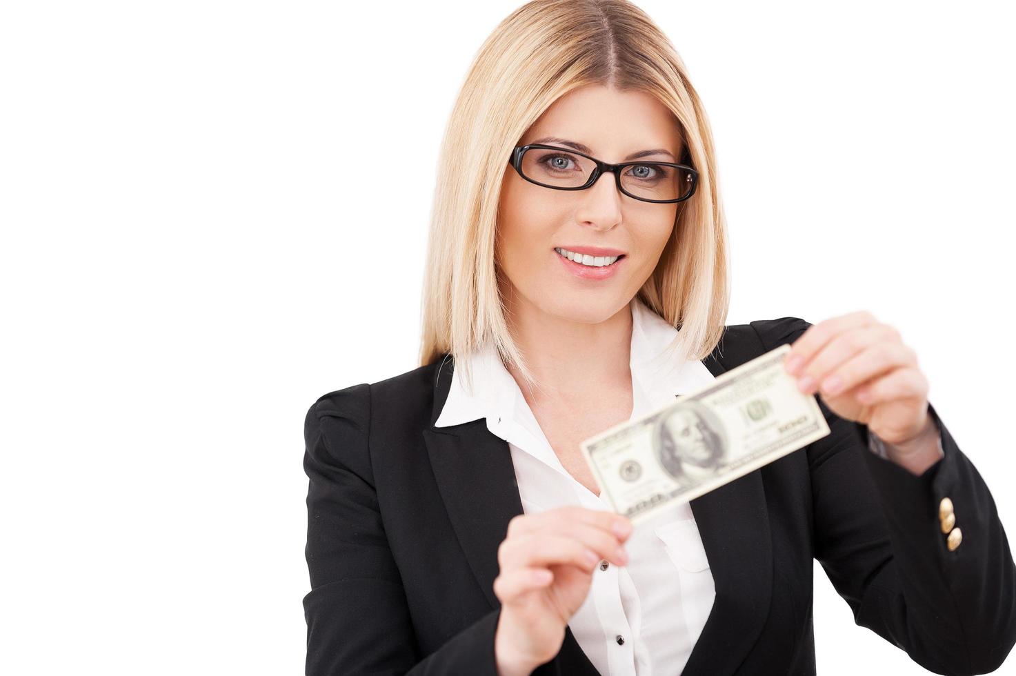 Money is a power. Confident mature businesswoman holding one hundred dollar bill and smiling while standing isolated on white photo