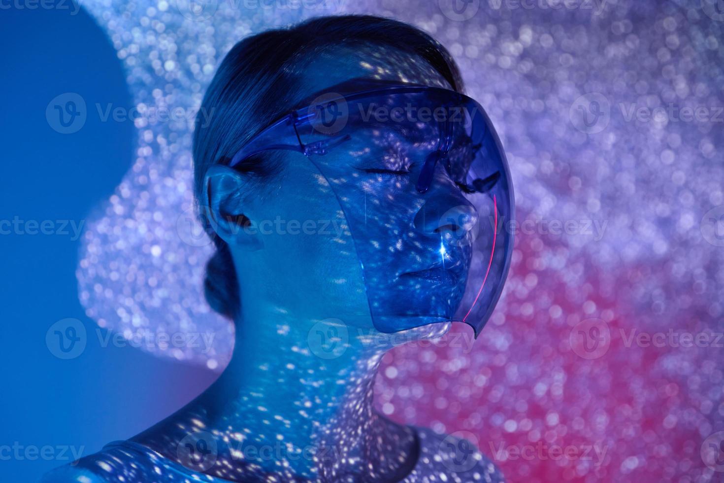 Confident young woman wearing futuristic glasses against colorful background photo