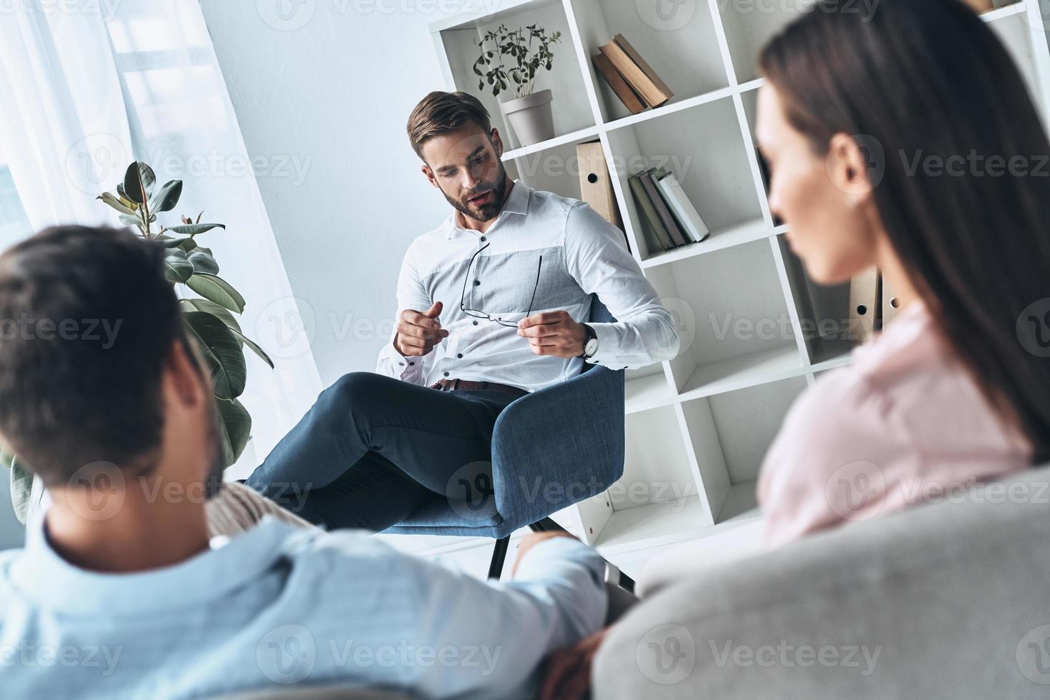 todos enfrentan dificultades. joven pareja casada hablando mientras se sienta en la sesión de terapia con el psicólogo foto