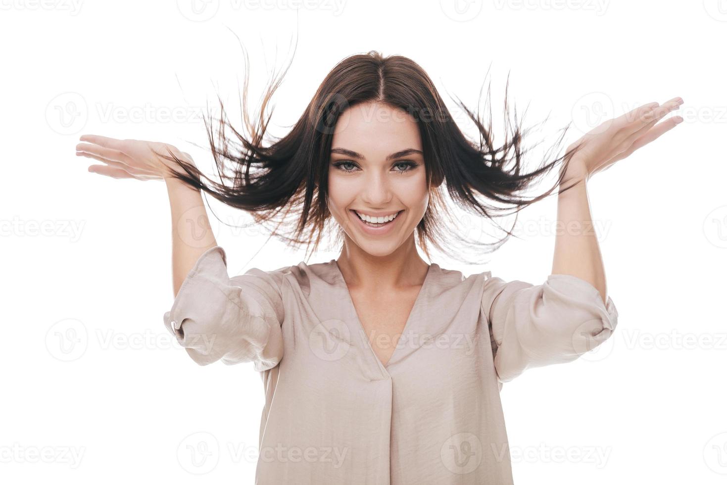 I love my hair. Attractive young woman touching her hair and smiling while standing against white background photo