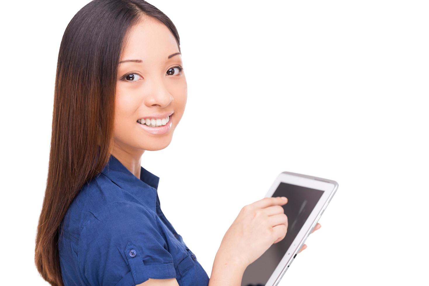 Taking advantages of digital age. Rear view of beautiful young Asian woman using digital tablet and looking over shoulder while standing isolated on white photo
