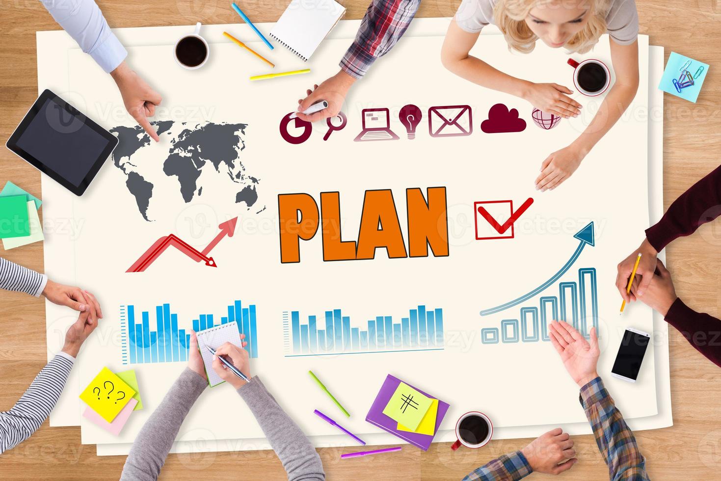 Planning together. Top view of paper with colorful sketches on it laying on the wooden table and people sitting around photo