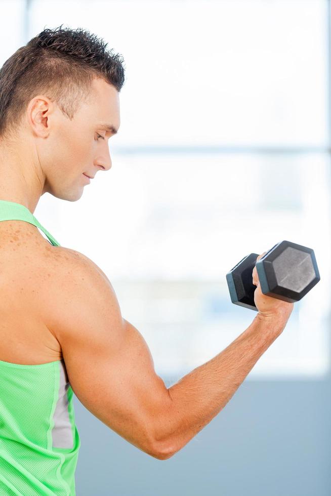 hombre haciendo ejercicio. hombre sano levantando pesas en un gimnasio foto