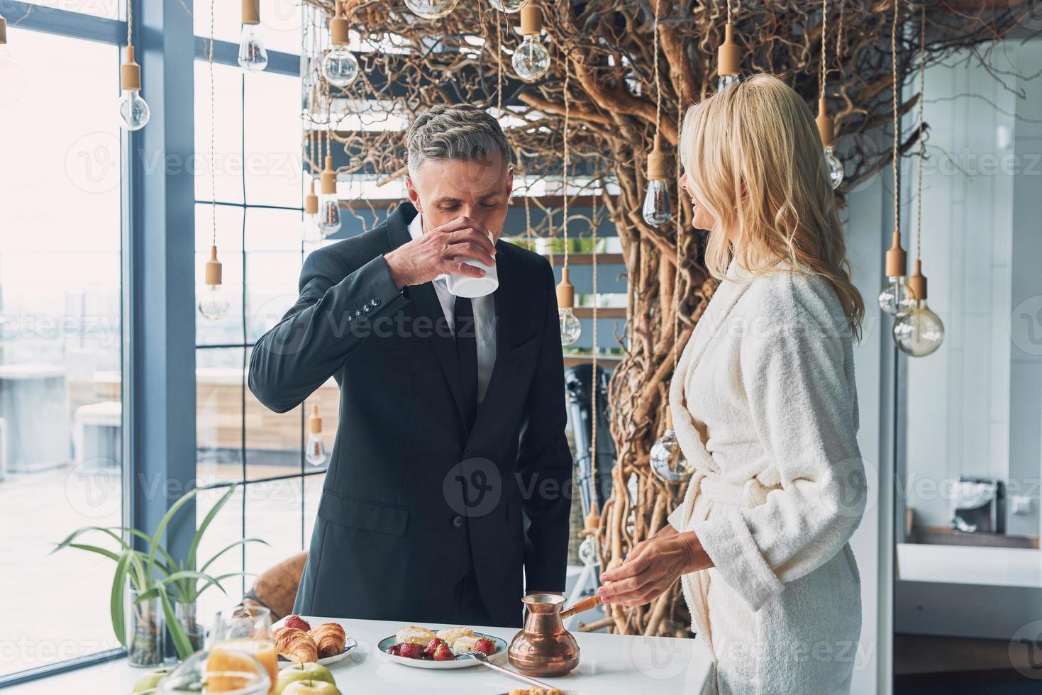 hermosa pareja madura disfrutando del desayuno juntos mientras pasan tiempo en la cocina doméstica foto