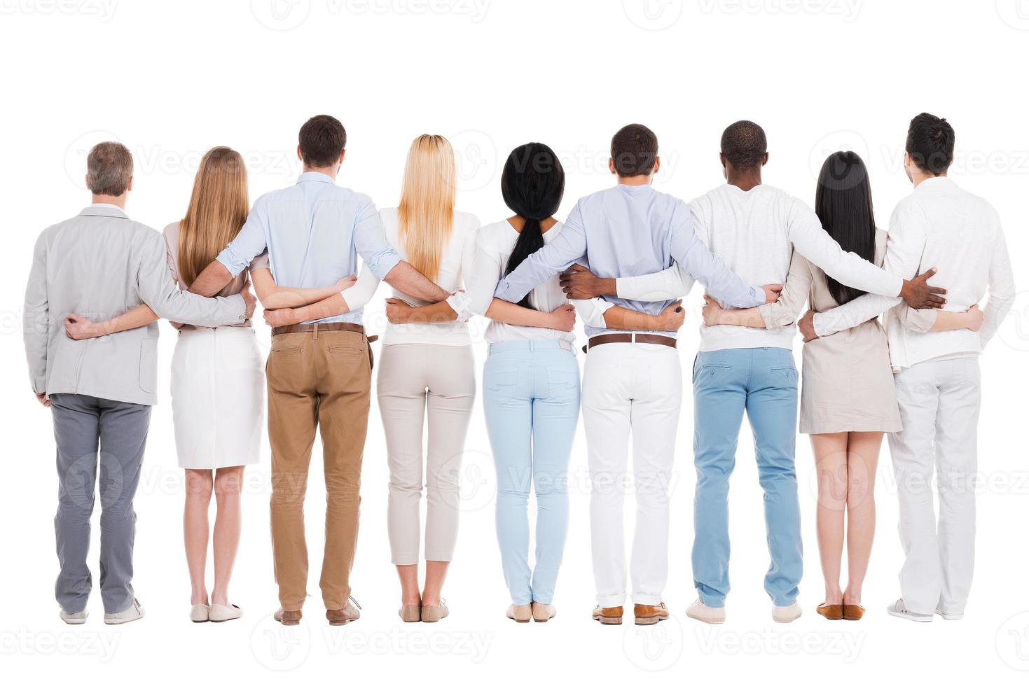 United team. Full length rear view of group of diverse people bonding to each other while standing against white background photo