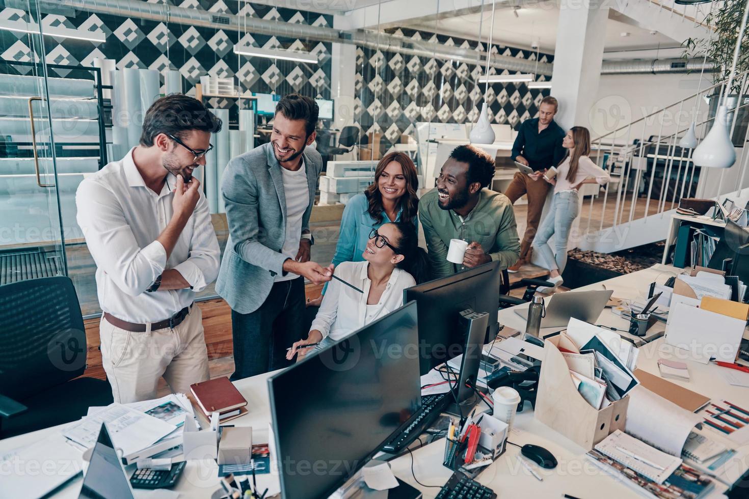 Group of young modern people in smart casual wear discussing business while working in the office photo