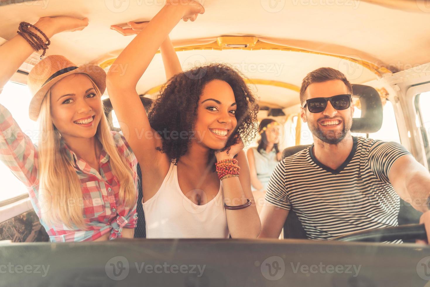 Enjoying great roadtrip with friends. Group of cheerful young people having fun while sitting inside of minivan photo