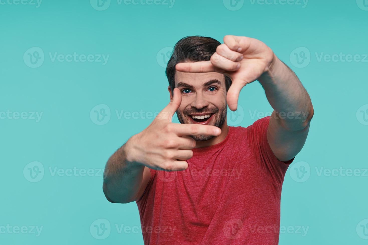 Handsome young smiling man in casual clothing looking at camera and gesturing photo