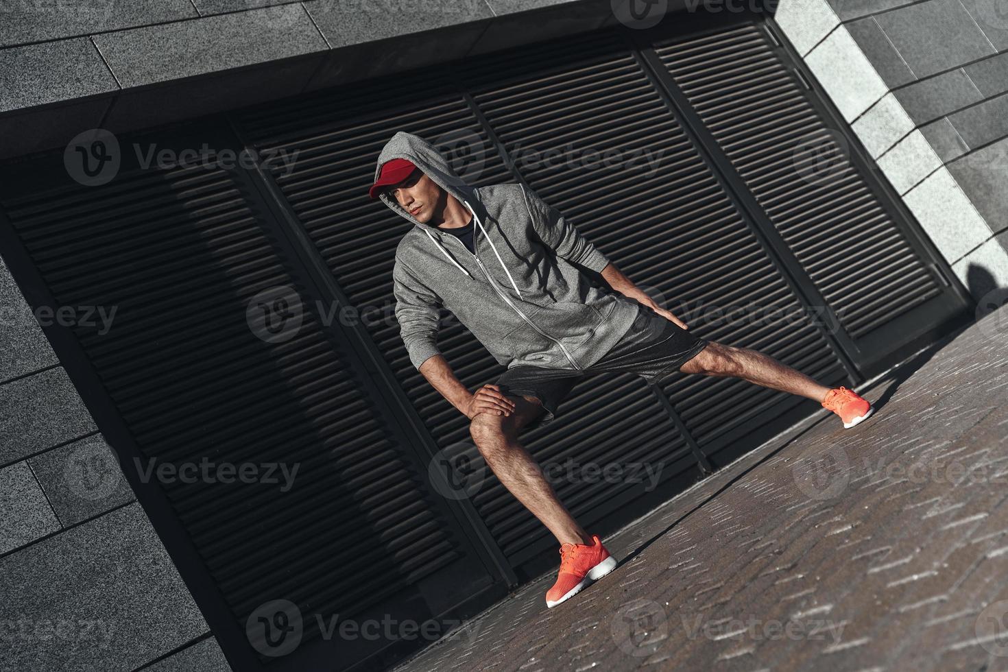 New champion. Full length of young man in sports clothing warming up while exercising outside photo