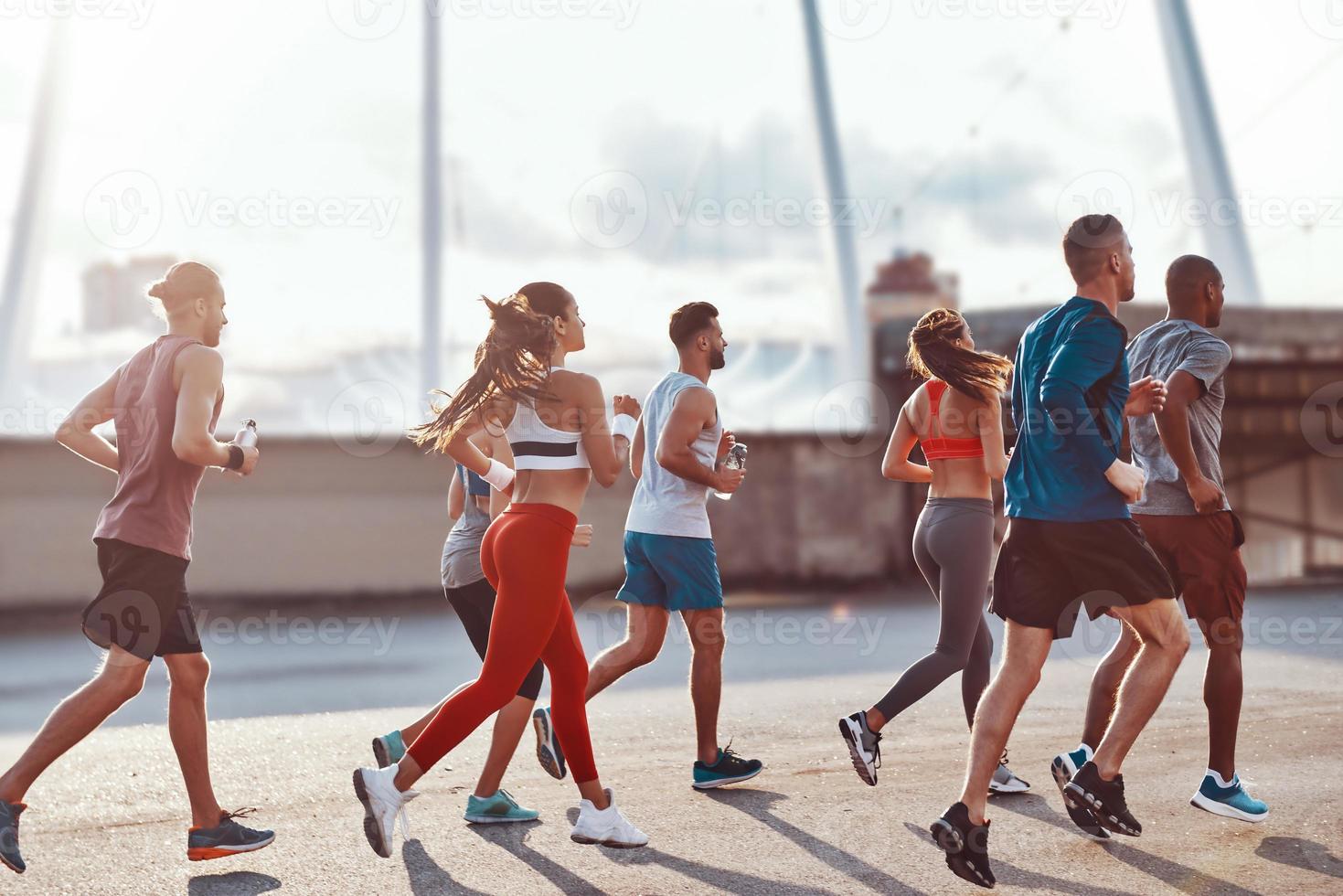 Group of young people in sports clothing jogging together outdoors photo