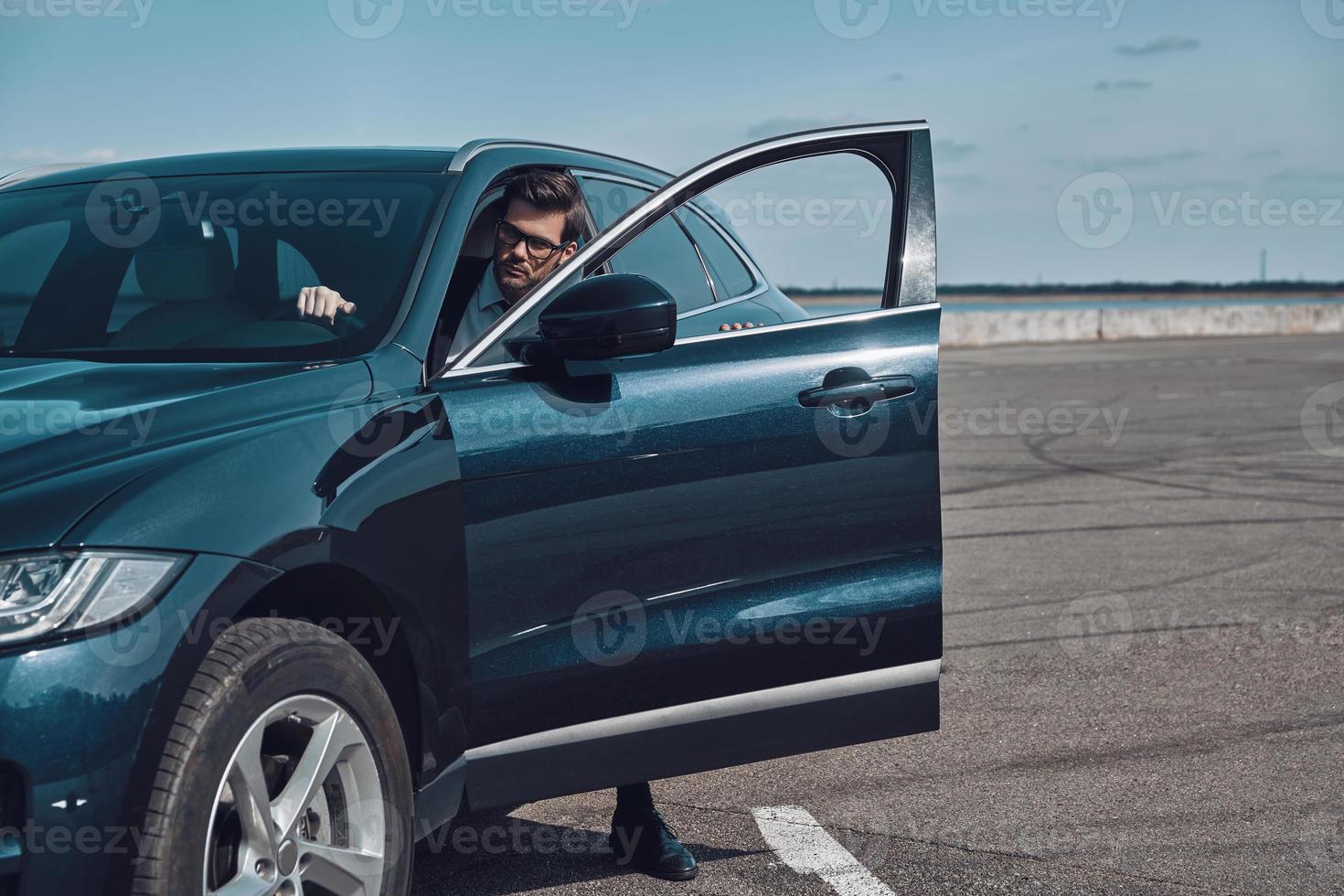 Luxury car. Handsome young man in business wear entering his car photo