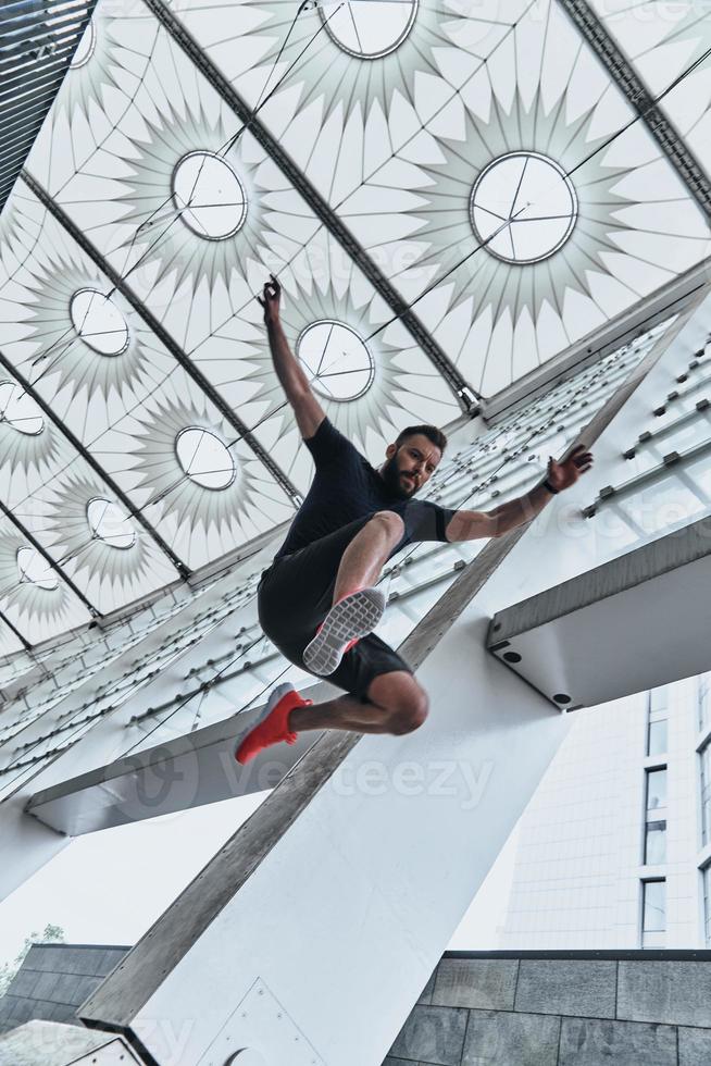 He is a new champion. Full length of handsome young man in sport clothing jumping while exercising outside photo