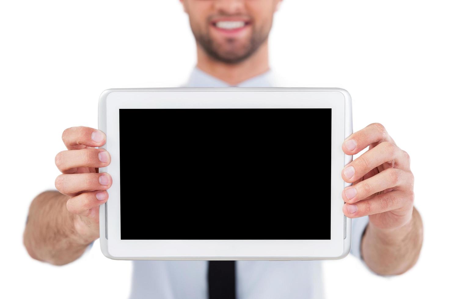 Copy space on digital tablet. Cropped image of cheerful young man in formalwear showing his digital tablet and smiling while standing isolated on white background photo