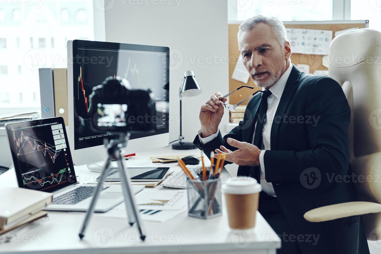 Senior man in elegant business suit using modern technologies while making social media video photo
