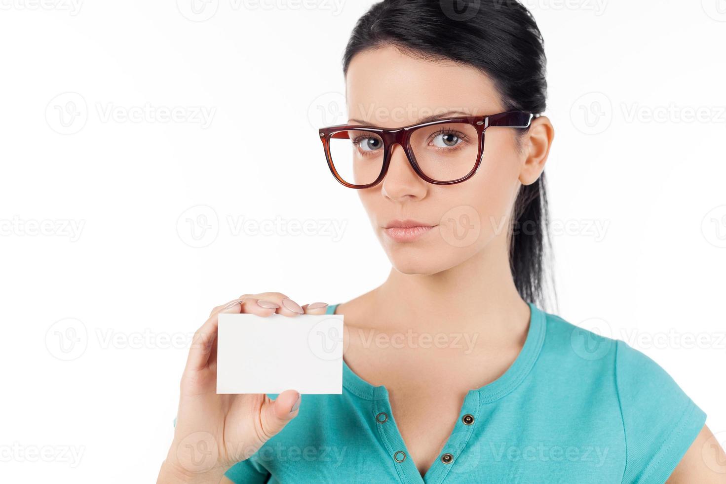 Woman with business card. Confident young woman in glasses holding business card in her hand and while standing isolated on white photo